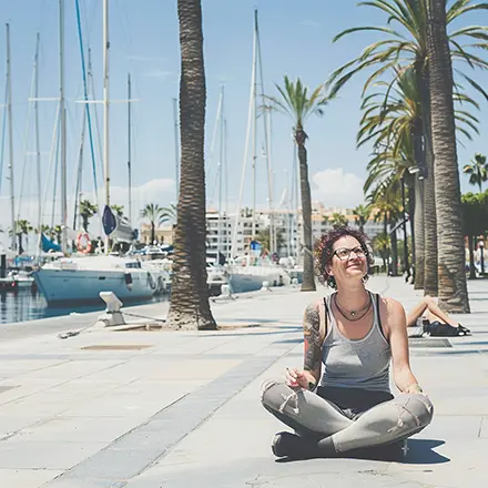 Mujer relajada y sonriente en el puerto, meditando antes del examen del curso PER